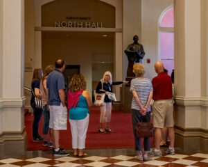 Volunteer Becky Moeggenberg with a tour group near the statue of Theodore Thomas in Music Hall.