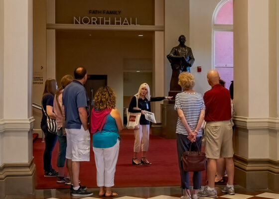 Volunteer Becky Moeggenberg with a tour group near the statue of Theodore Thomas in Music Hall.