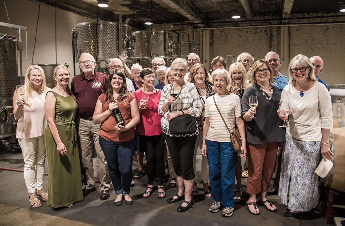 The volunteers who attended the celebration, with winery owner Kate MacDonald (holding the bottle of wine) and Ramona Toussaint, second from right, SPMH Tour Director.