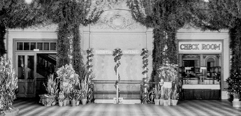 The foyer is decorated with leafy vines hanging above fresh floral arrangements.