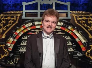 Organist and arranger Clark Wilson in front of the Mighty Wurlitzer Organ