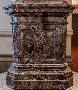 The name "Springer" in gilt on the front of pedestal of the statue of Reuben R. Springer in Cincinnati Music Hall.